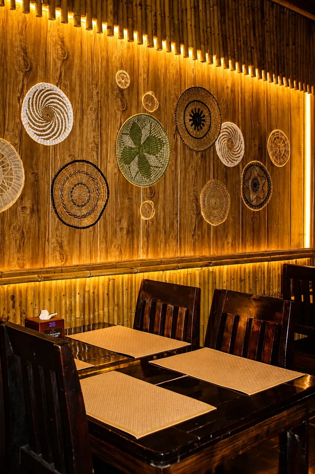 A table laid with woven mats beneath a wall of hanging baskets